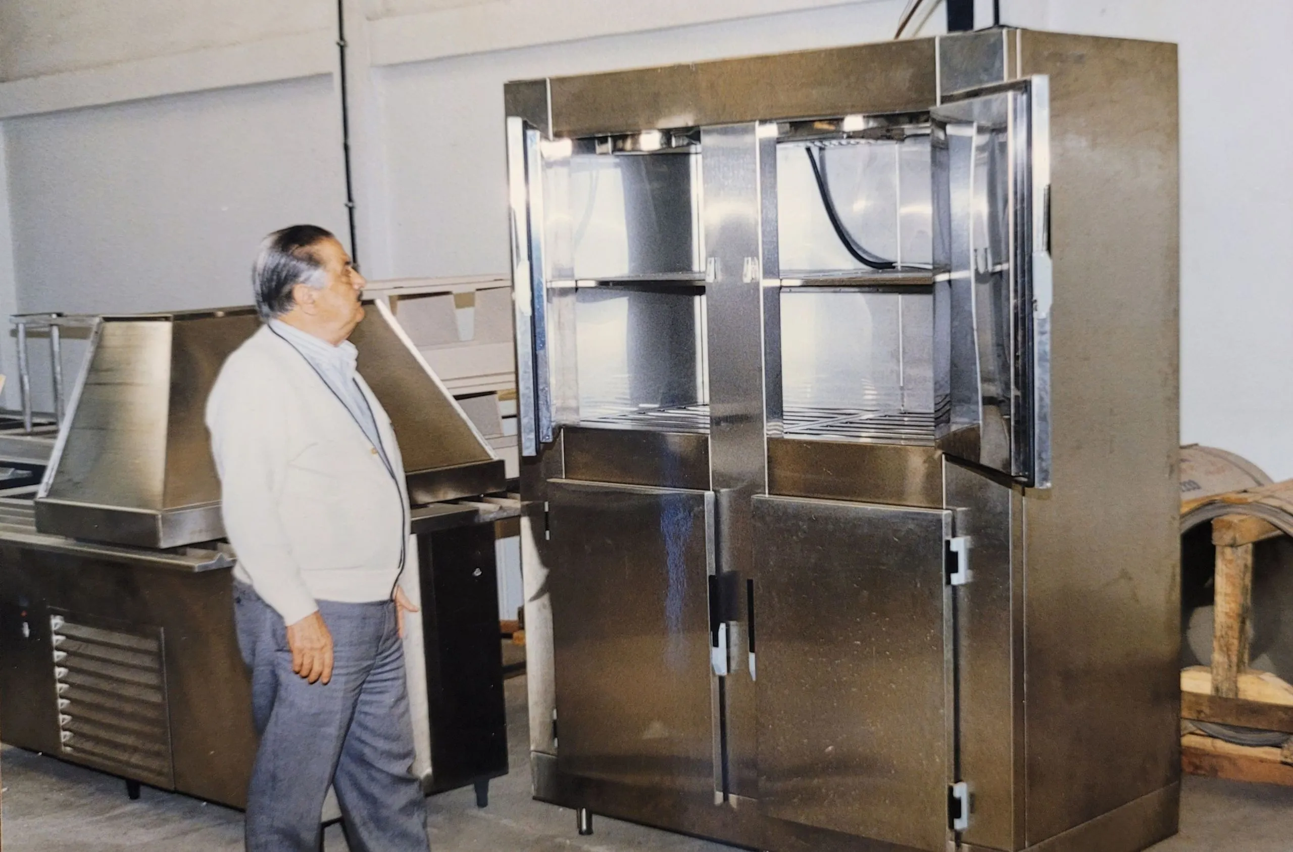 Funcionário ao lado de um refrigerador comercial de aço inox com as portas abertas